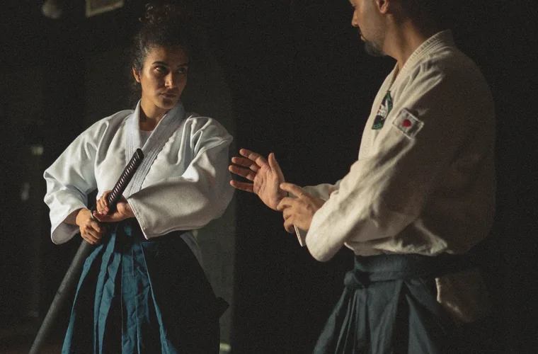 Práctica tradicional de Aikido con hakama y arma de madera en el dojo
