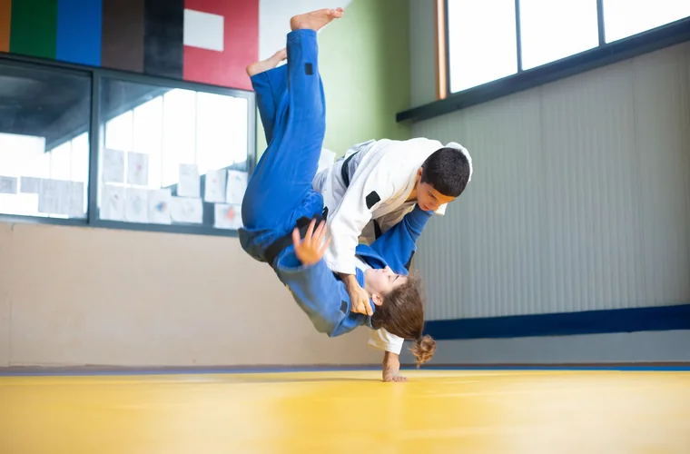 Proyección de judo: un judoka lanza a su compañero por el aire